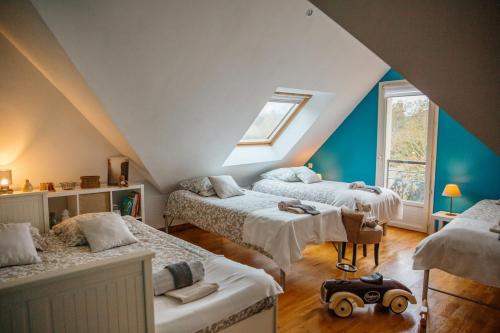 Cette chambre mansardée comprend 3 lits et une fenêtre. dans l'établissement La Maison du Pont des 2 Rives, à Guipry-Messac