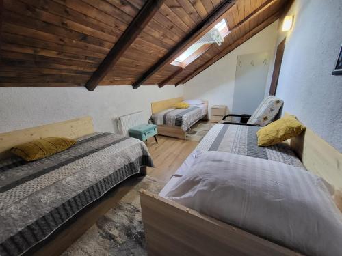 a bedroom with two beds and a wooden ceiling at Koča sredi gozda in Kanal