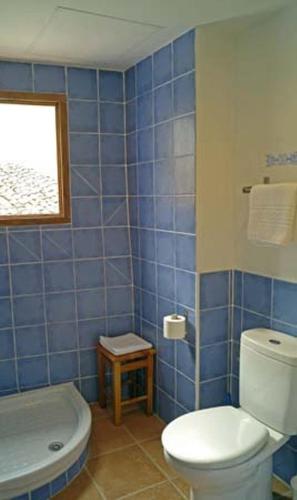 a blue tiled bathroom with a toilet and a sink at Casa Figueretes in Finestrat