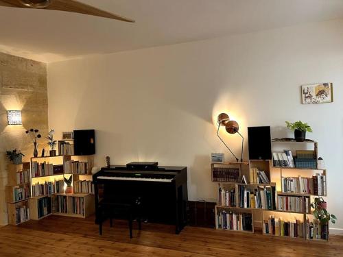 a living room with a piano and book shelves at Grand appartement central aéré avec terrasse in Bordeaux