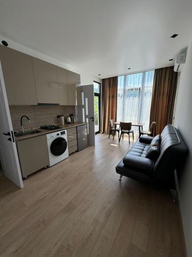 a living room with a black couch and a kitchen at Veranda White House in Batumi