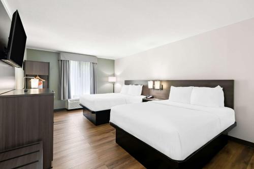 a hotel room with two beds and a flat screen tv at Quality Inn Merrimack - Nashua in Merrimack