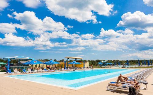 une piscine dans un complexe hôtelier avec des gens allongés sur des chaises longues dans l'établissement Waves & Whispers Apartments - acces gratuit piscina, à Olimp