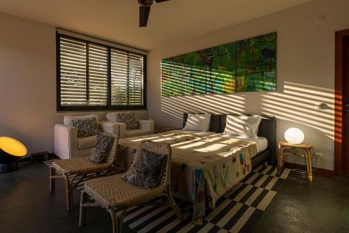 a bedroom with a bed and chairs and a couch at The Pine Tree Comporta Villa in Carvalhal