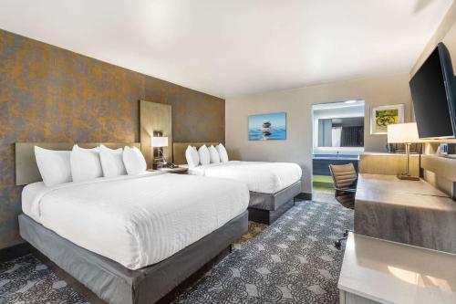a hotel room with two beds and a flat screen tv at Clarion Inn Murfreesboro Old Fort Pkwy in Murfreesboro