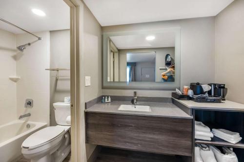 a bathroom with a sink and a toilet and a mirror at Clarion Inn Murfreesboro Old Fort Pkwy in Murfreesboro