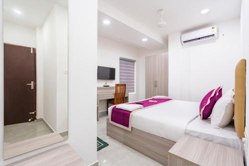 a white bedroom with a bed and a desk at GRACE REGENCY in Ernakulam