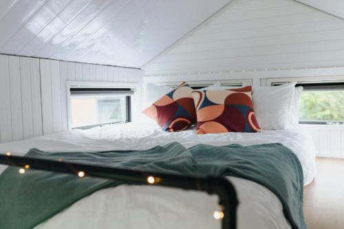 a bedroom with a bed with white sheets and pillows at Sweet Hart 1 by Tiny Away in Tamahere