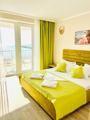 a bedroom with a large yellow bed with a balcony at KIR House On The Beach in Eforie Nord