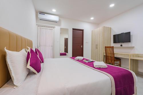 a bedroom with a large bed with purple and white pillows at GRACE REGENCY in Ernakulam