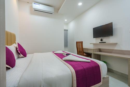 a bedroom with a bed and a desk with a tv at GRACE REGENCY in Ernakulam