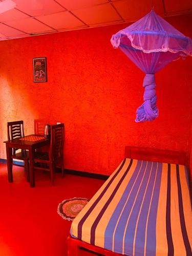 a bedroom with a red wall with a bed and a table at Hotel Hideaway Garage in Dambulla