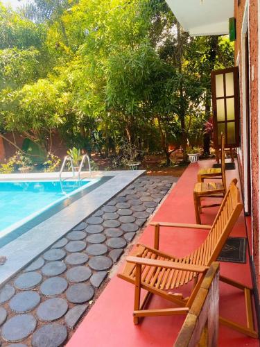 a swimming pool with two wooden benches next to a pool at Hotel Hideaway Garage in Dambulla