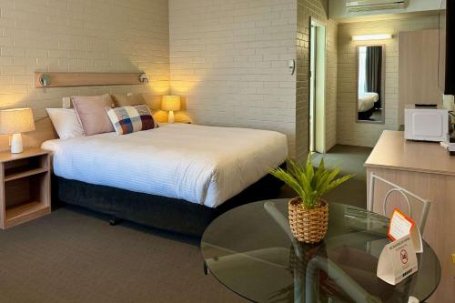 a bedroom with a bed with a glass table and a table at Econo Lodge Gateway Tamworth in Tamworth