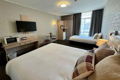 a hotel room with two beds and a flat screen tv at Econo Lodge Gateway Tamworth in Tamworth