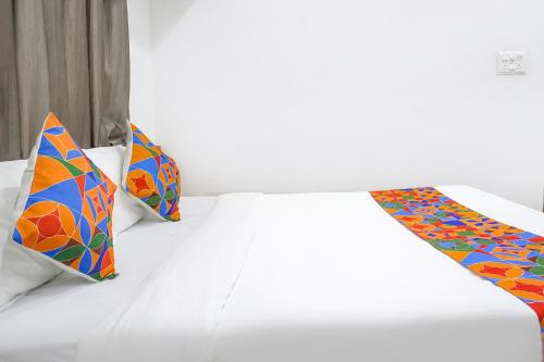 a white bed with two colorful pillows on it at FabHotel The White House Inn - EON IT Park in Pune