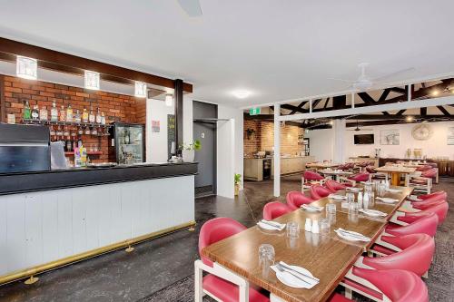 a restaurant with wooden tables and red chairs at Econo Lodge Gateway Tamworth in Tamworth