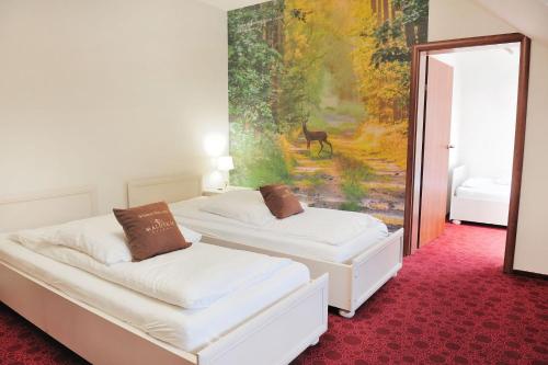 two beds in a room with a painting on the wall at Malutkie Resort in Radomsko