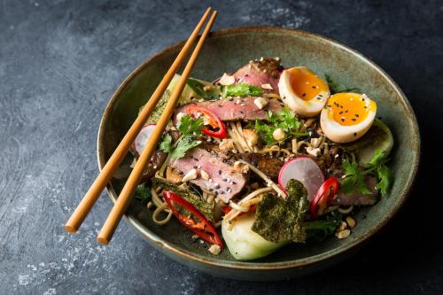 a bowl of food with meat and eggs and chopsticks at Dusit Thani Dubai in Dubai