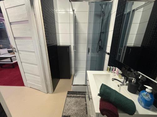a bathroom with a shower and a sink and a mirror at Apartamenty na Górce in Olsztyn