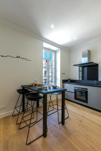 une cuisine avec une table et des chaises dans une pièce dans l'établissement Appartement intramuros hyper centre Avignon, à Avignon