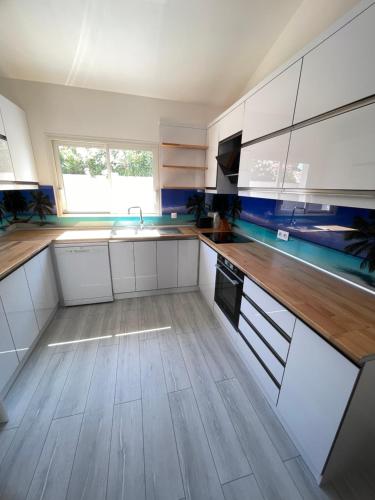 une cuisine avec des armoires blanches et un plancher en bois dans l'établissement Maison du Paşa, à Port-la-Nouvelle