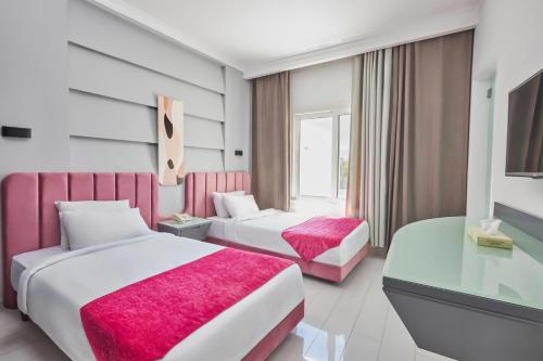 two beds in a hotel room with pink sheets at Golden Palace Marina Hotel in El Alamein