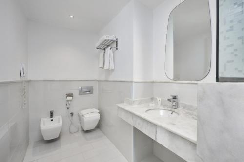 a white bathroom with a toilet and a sink at Golden Palace Marina Hotel in El Alamein