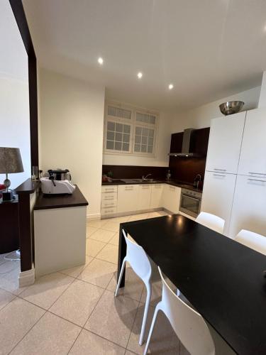 une cuisine avec une table noire et des armoires blanches dans l'établissement Superbe appartement de 100m2 face à la mer Dans un ancien palace, à Menton