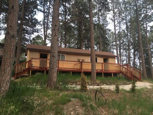 a house with a large deck in the woods at Cabin 2 Brand new Rental car available in Custer