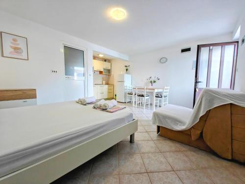 a white bedroom with a bed and a kitchen at Robinson Edita in Bogomolje