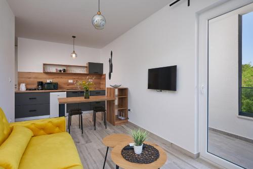 a living room with a yellow couch and a kitchen at Urban Apartment Endji in Močići