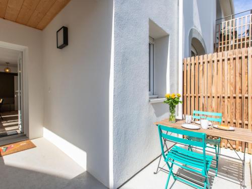 une terrasse avec une table en bois et une chaise bleue dans l'établissement Apartment Cap Océan-5 by Interhome, à Capbreton