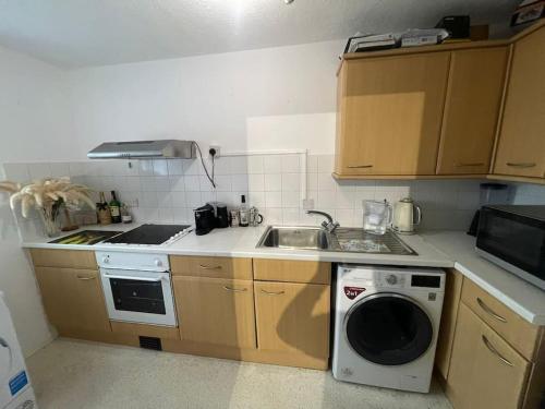 a kitchen with a washing machine and a sink at Private apt close to train station in London