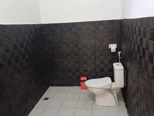a bathroom with a toilet and a brick wall at Black Sweet Homestay Dua in Gili Islands