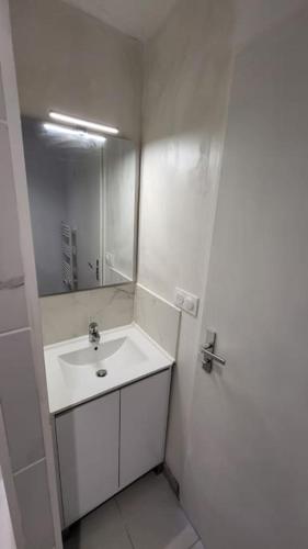 une salle de bain blanche avec un lavabo et un miroir dans l'établissement Studio contemporain avec parking gratuit, à Castelnau-dʼEstrétefonds
