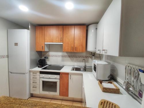 una cucina con elettrodomestici bianchi e armadietti in legno di Retiro MonteMar a La Manga del Mar Menor