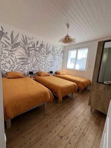 une chambre avec trois lits avec une fresque murale dans l'établissement Ô Lavoir, aux Épesses