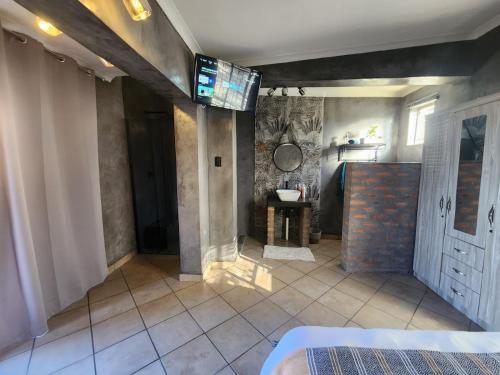 a bedroom with a tv on the wall and a bathroom at A Step Ahead in Klerksdorp