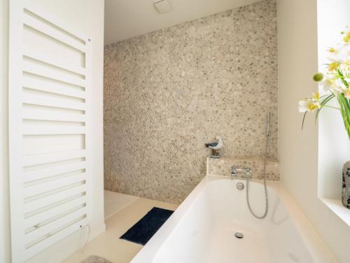 a bathroom with a bath tub and a window at Holiday Home La Gabane quiet but central house by Interhome in De Haan