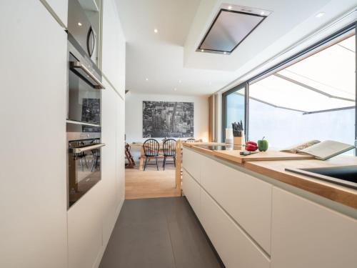 a kitchen with white cabinets and a large window at Holiday Home La Gabane quiet but central house by Interhome in De Haan