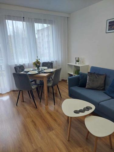 a living room with a blue couch and a table and chairs at Apartament Centrum przy Placu Zwycięstwa in Gryfice
