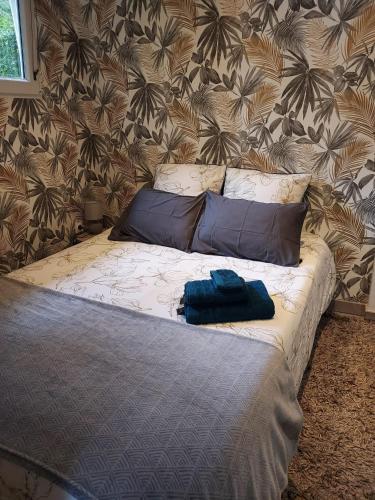 - un lit avec 2 oreillers bleus et un mur dans l'établissement A l'orée du bois, à Saint-Sébastien-sur-Loire