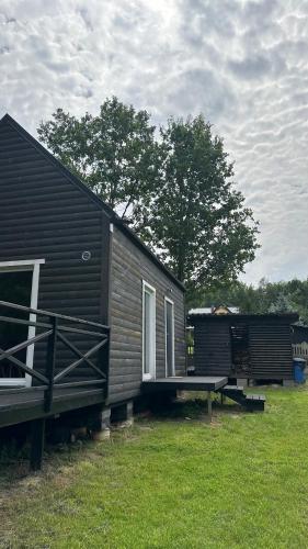 a black tiny house with a bench next to it at Domek nad Uroczyskiem in Piotrowice