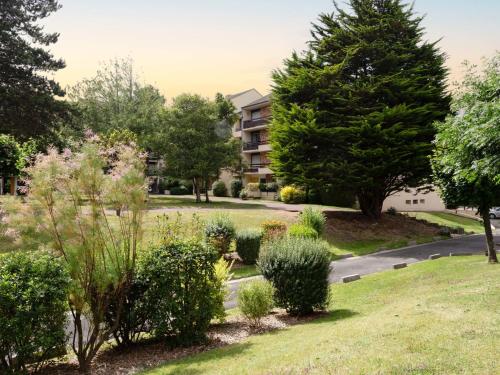 un parc avec des arbres et des buissons et un bâtiment dans l'établissement Apartment Le Sporting-17 by Interhome, à Cabourg