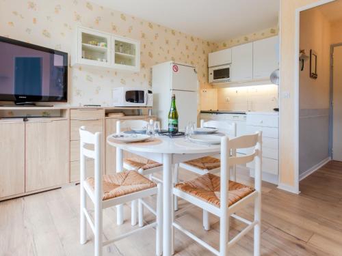 Il comprend une cuisine avec une table et des chaises blanches ainsi qu'une télévision. dans l'établissement Apartment Fleur Marine-35 by Interhome, à Cabourg