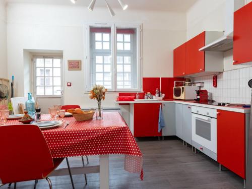 une cuisine avec des placards rouges et une table avec un chiffon de table dans l'établissement Apartment Saint Benoît by Interhome, à Saint-Malo