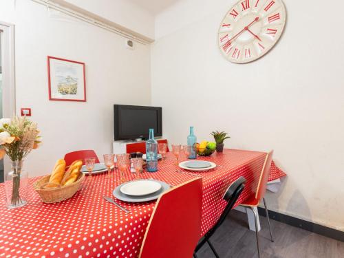 une table rouge avec des chaises rouges et une horloge sur le mur dans l'établissement Apartment Saint Benoît by Interhome, à Saint-Malo