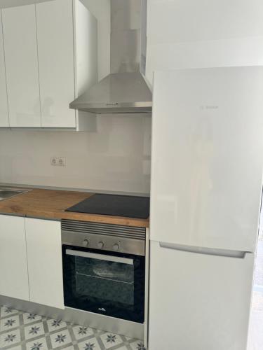 a kitchen with white cabinets and a stove top oven at Casa Rural El Almendro in Fernán Pérez