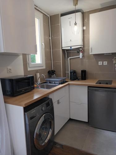 une cuisine avec une machine à laver et un évier dans l'établissement Superbe appart à 15 min à pied du stade de France, à Aubervilliers